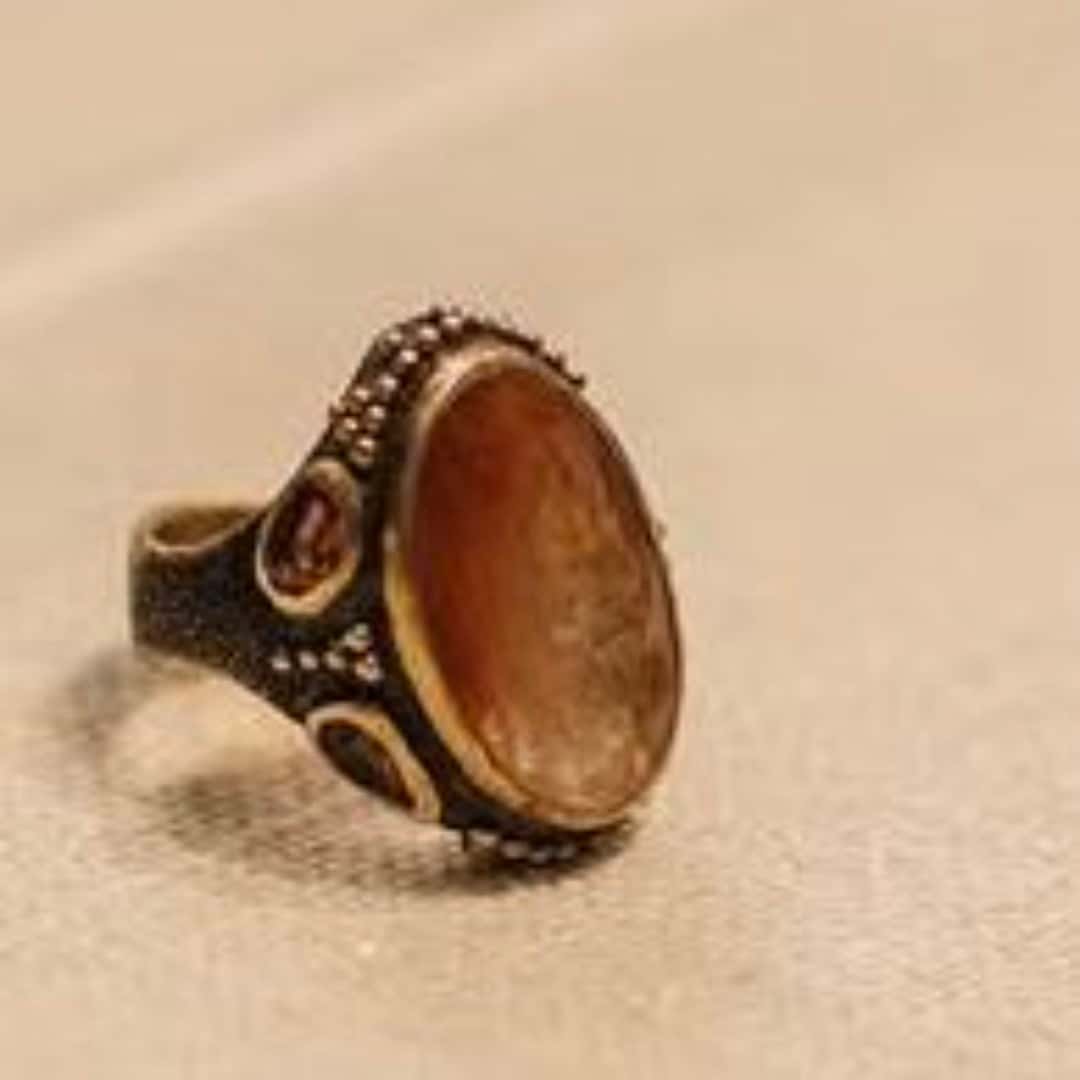 Phone photograph of an ornate amber ring on pale fabric