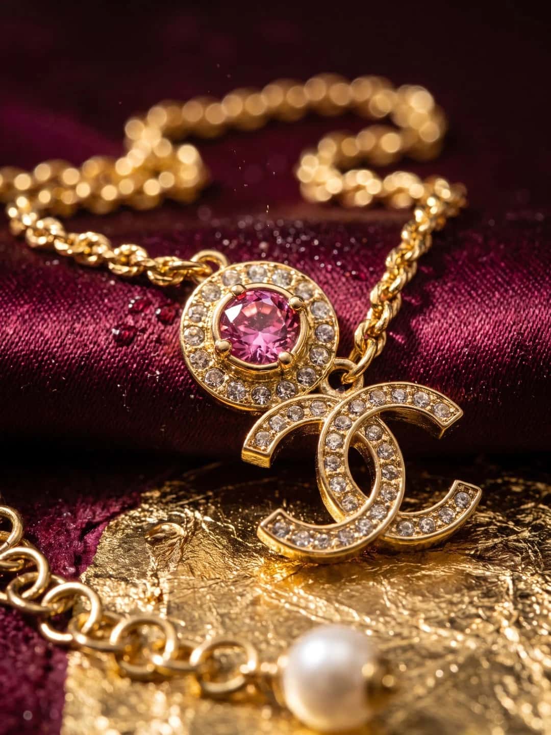 Art-directed close-up of the same gold pendant necklace on burgundy velvet with warm metallic accents