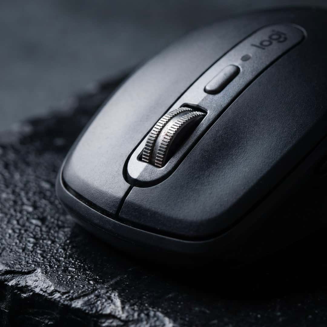 Art-directed close-up of the same black Logitech mouse on a dark textured surface