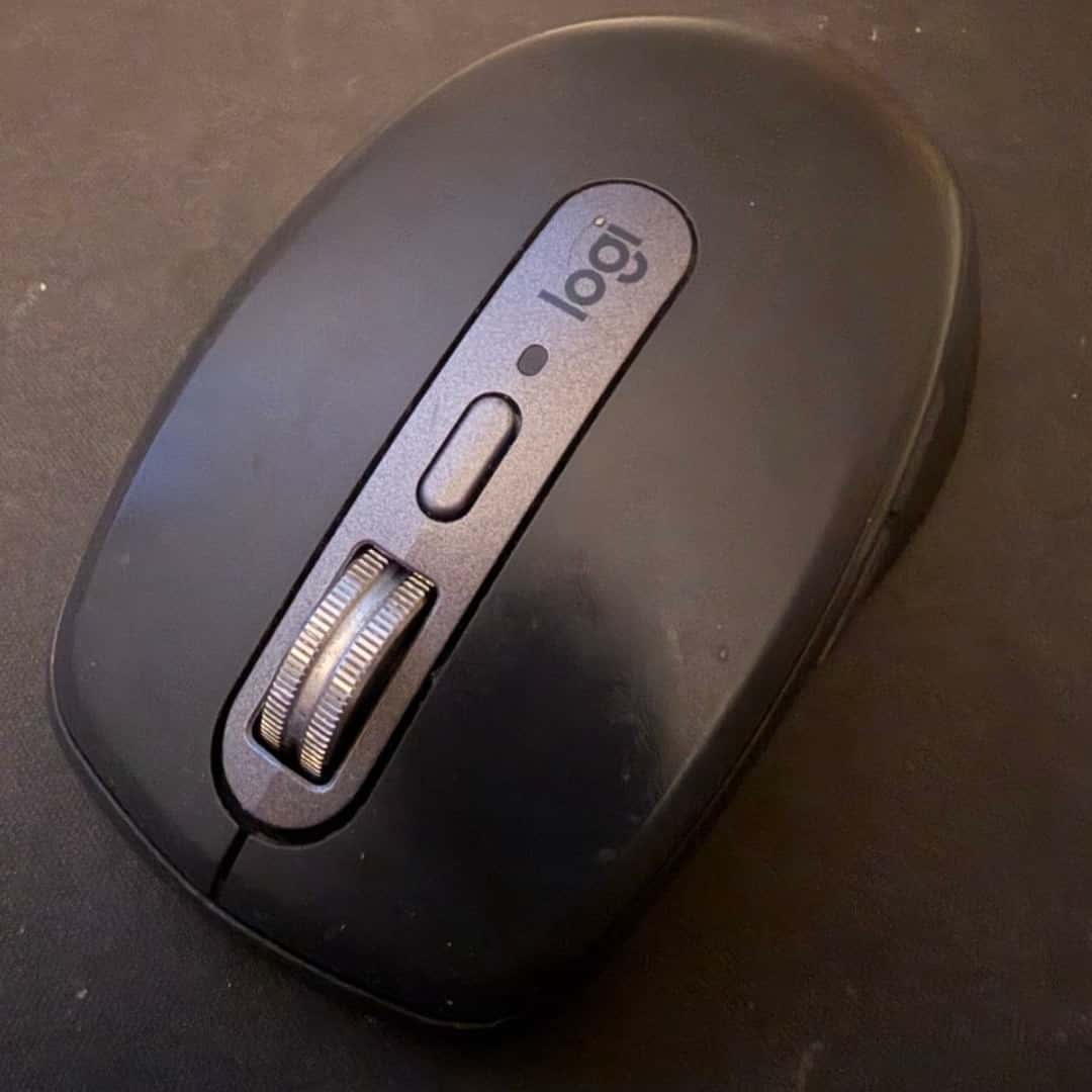Phone photograph of a black Logitech mouse on a desk