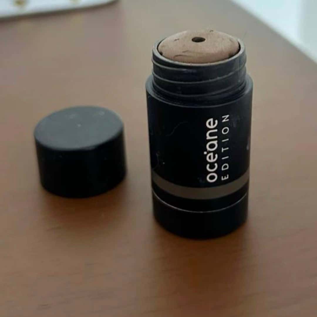 Phone photograph of an open black makeup stick and cap on a wooden table