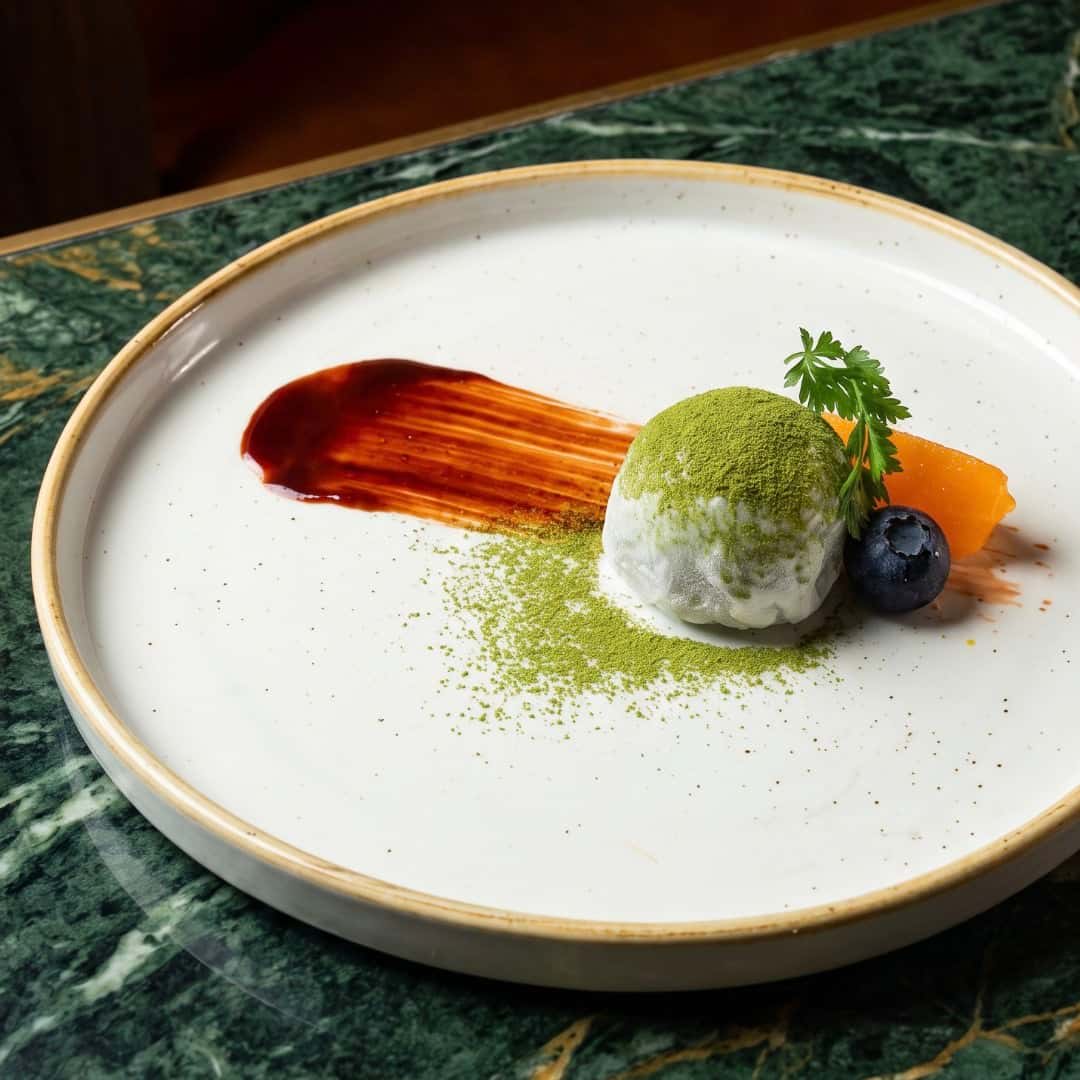 Art-directed photograph of the same matcha dessert on a white plate over green marble