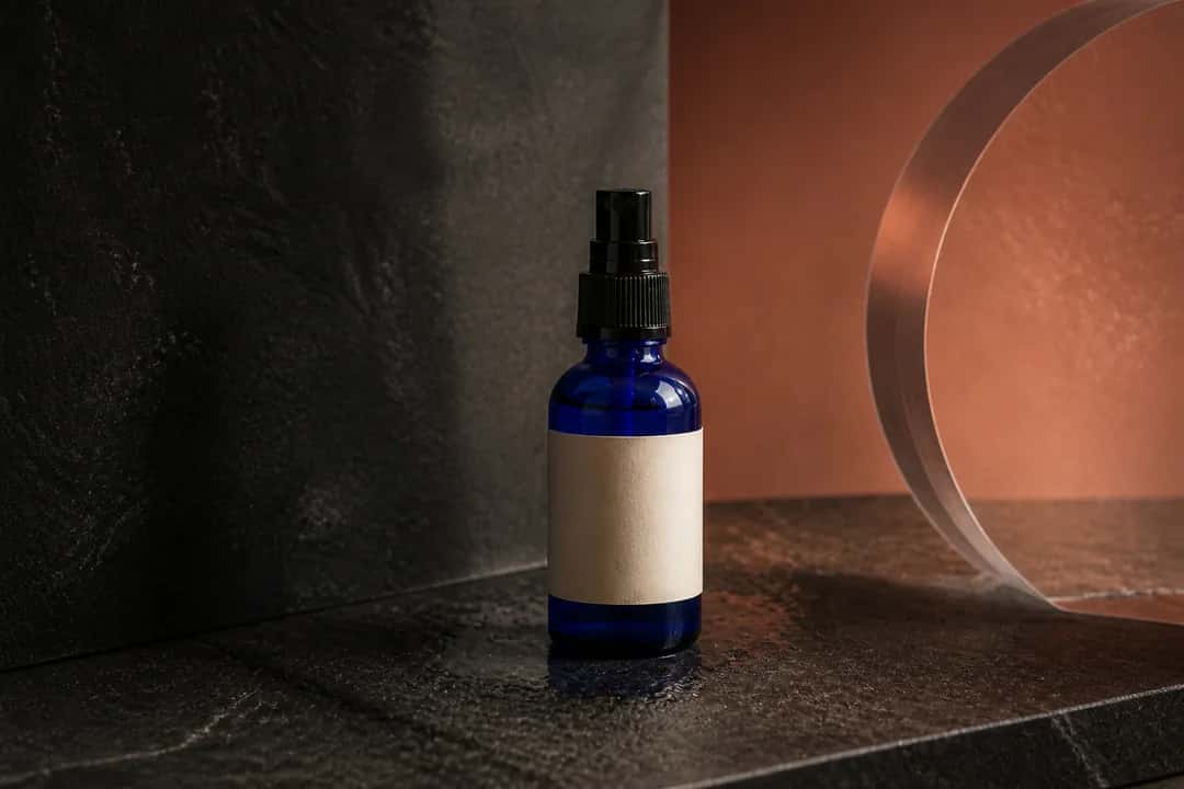 Finished campaign photograph of the cobalt-blue bottle on a dark stone and terracotta set.