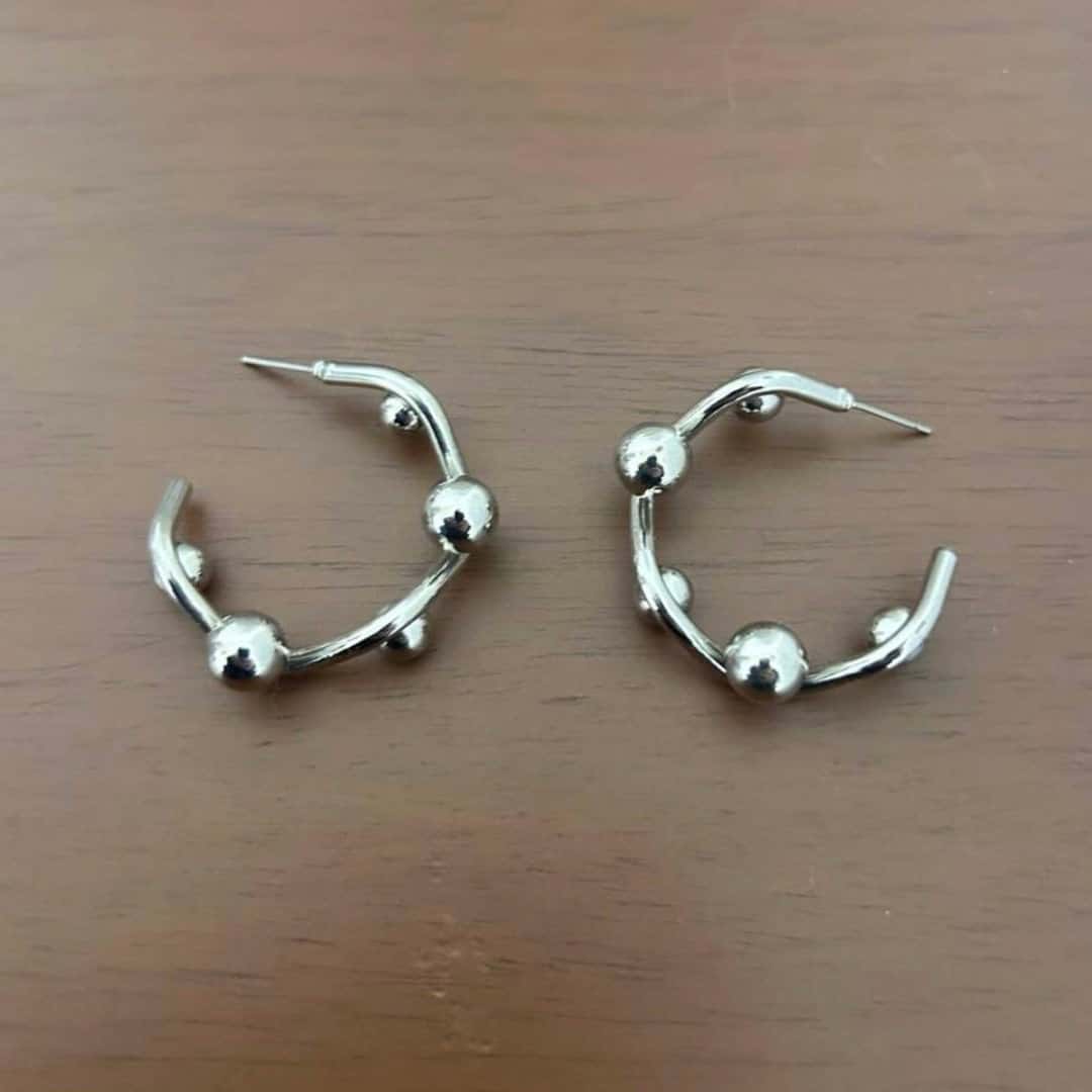 Phone photograph of silver ball hoop earrings on a wooden table