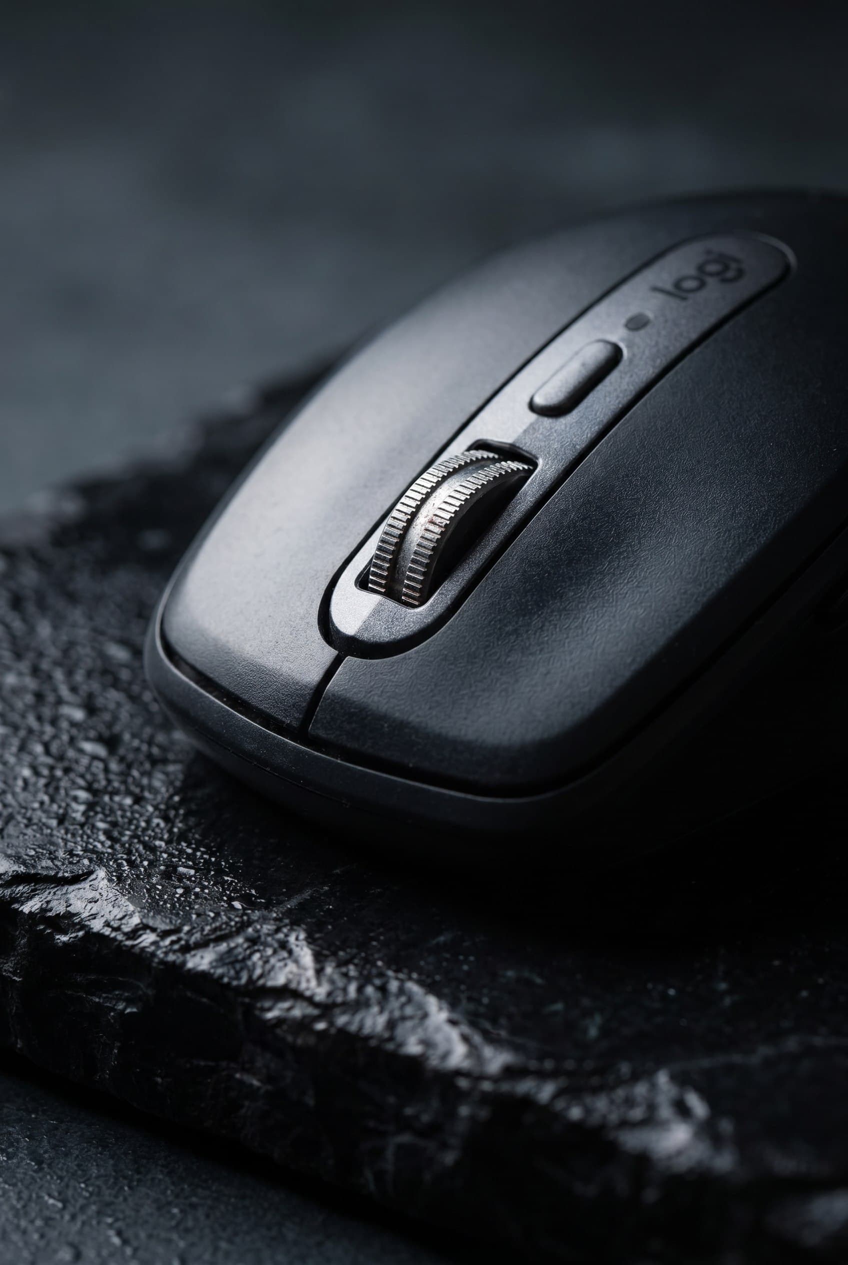 Art-directed campaign photograph of the same black mouse on a dark textured surface