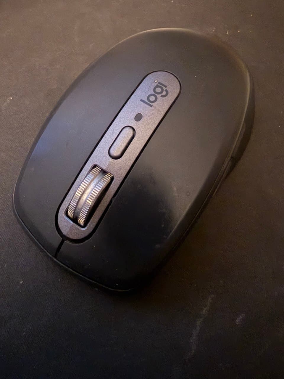 Phone photograph of a black computer mouse on a desk